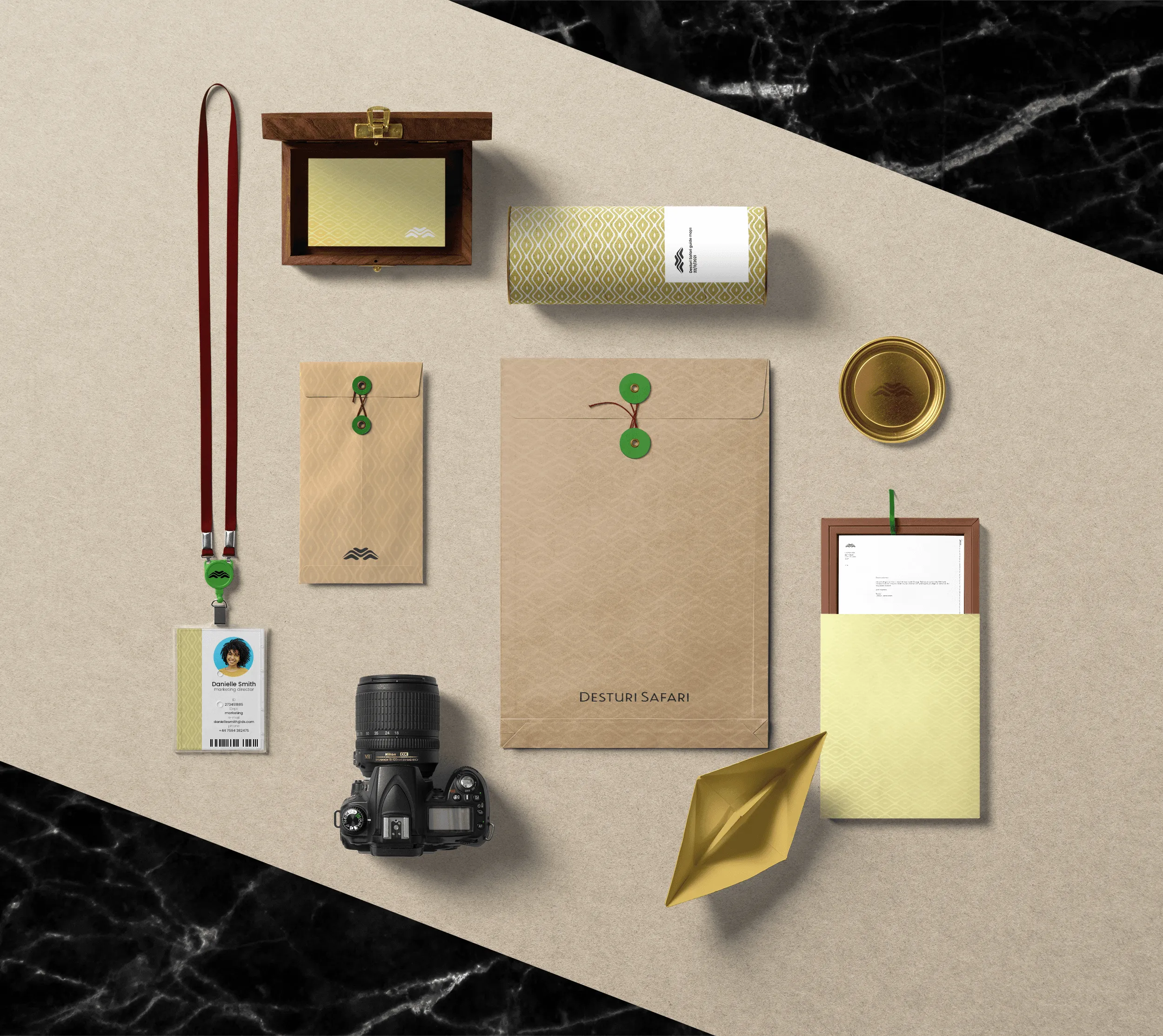 Flatlay of Desturi Safari branded items including ID badge, camera, envelopes, box, and letterhead.