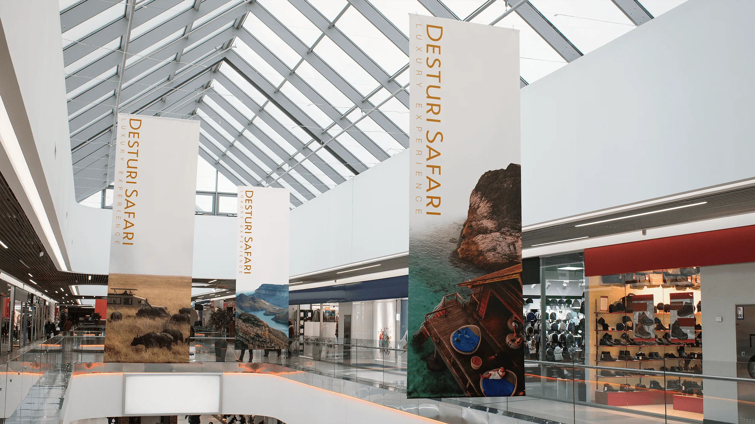 Shopping mall hallway with hanging banners advertising Desturi Safari luxury safari experience.